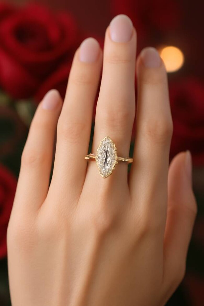 Image: Selena Gomez-inspired marquise lab-grown diamond engagement ring on hand with yellow gold pavé band against romantic Valentine