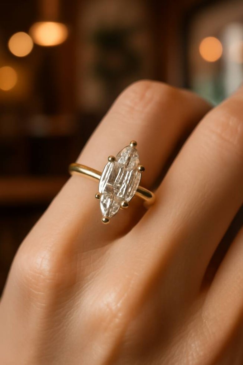 Image: Stunning close-up of Dutch marquise engagement ring on hand showing the distinctive broader center, softly tapered points, and step-cut facets creating linear light patterns against romantic lifestyle background - Captures the rare cut